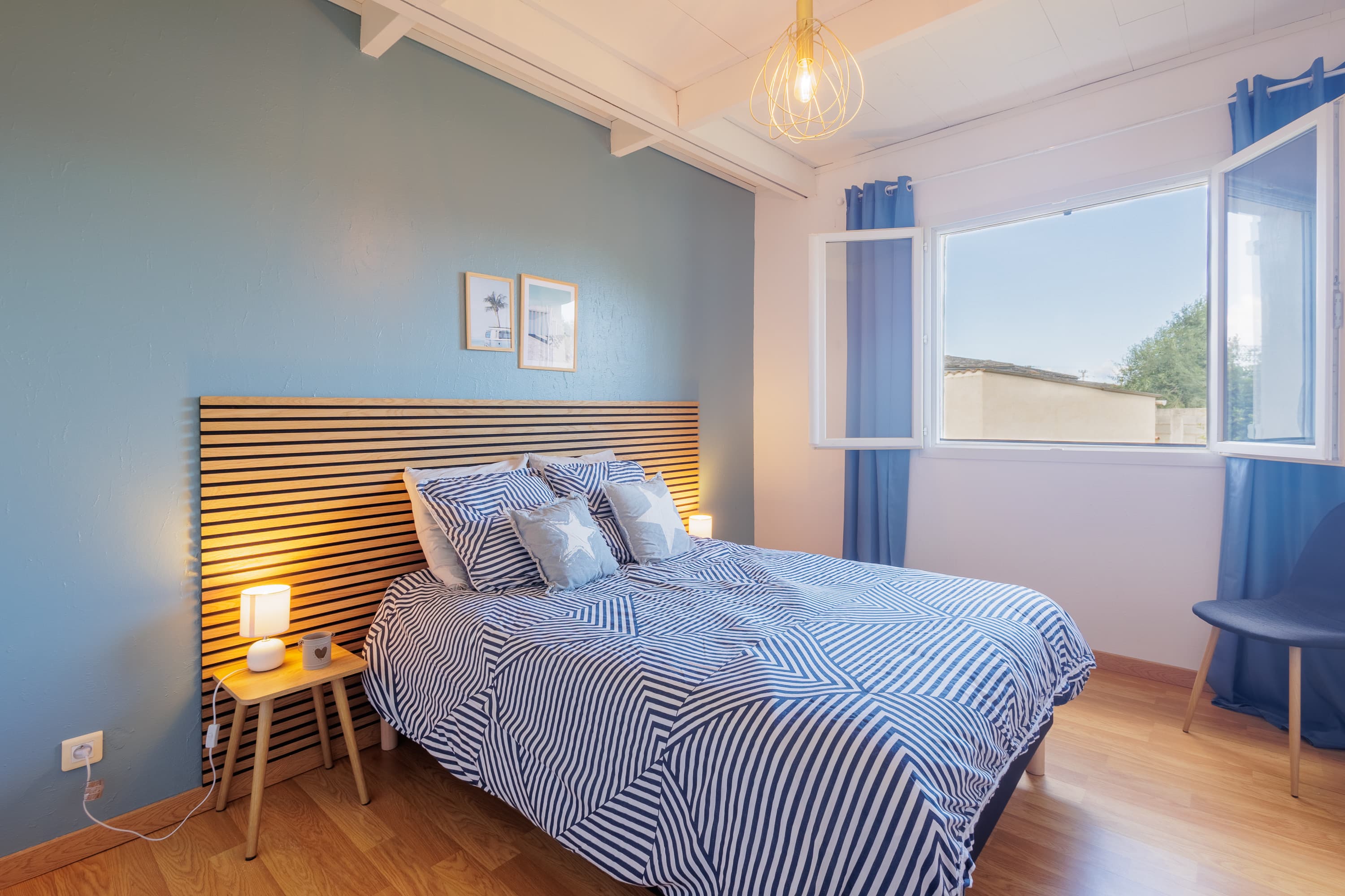 Chambre double aux tons bleus, lit confortable et grande fenêtre